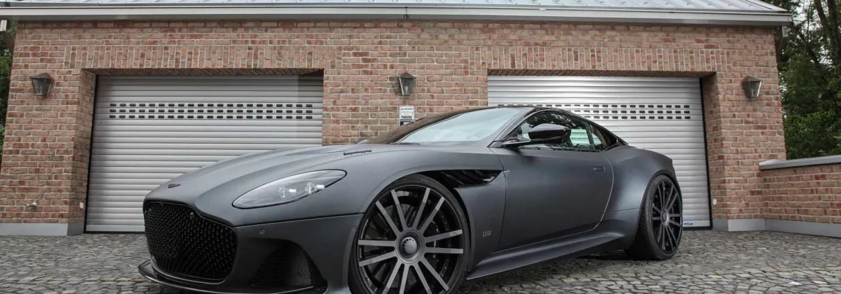 front side view aston martin dbs superleggera in front of garage wearing 22 inch wheels from wheelsandmore tuning